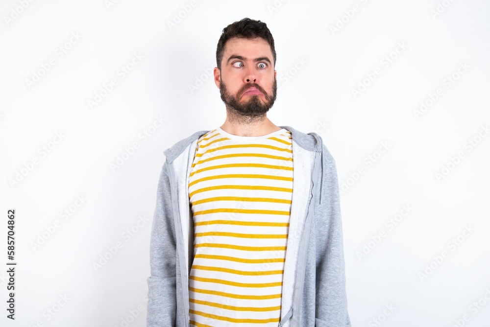 Young caucasian mán wearing trendy clothes over white background making grimace and crazy face, screaming out of control, funny lunatic expressing freedom and wild. Young caucasian mán wearing trendy clothes over white background making grimace and crazy face, screaming out of control, funny lunatic expressing freedom and wild.