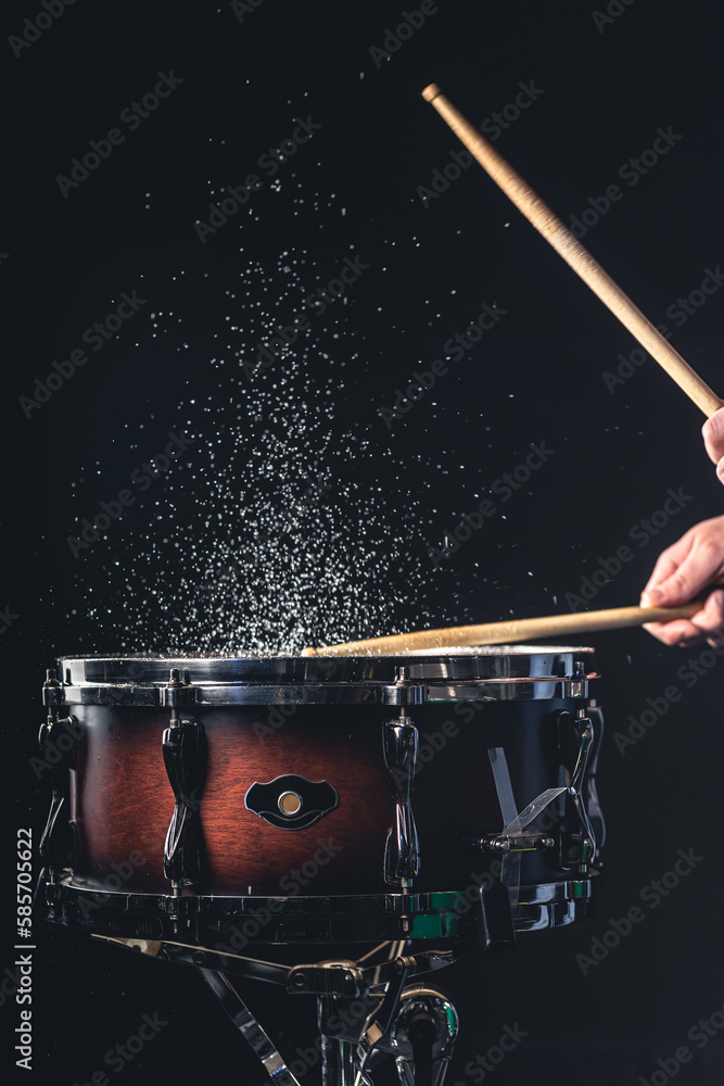 Drummer using drum sticks hitting snare drum with splashing water