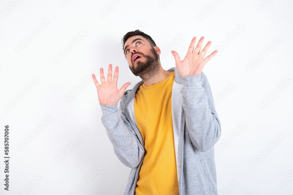Φωτογραφία Young caucasian mán wearing trendy clothes over white background keeps palms forward and looks with fright above on ceiling tries to defense herself from invisible danger opens mouth