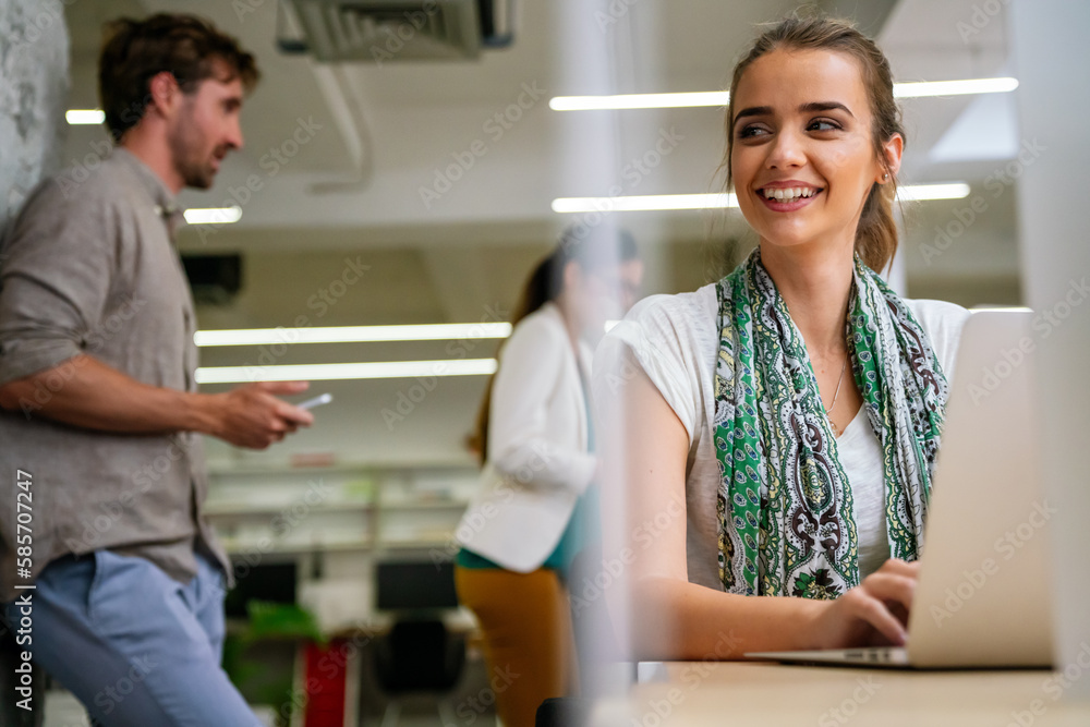 Successful young businesswoman working on laptop in office with colleagues at the background. Successful young businesswoman working on laptop in office with colleagues at the background.