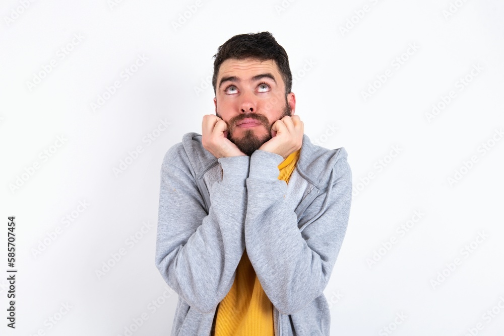 Portrait of sad Young caucasian mán wearing trendy clothes over white background hands face look empty space Portrait of sad Young caucasian mán wearing trendy clothes over white background hands face look empty space