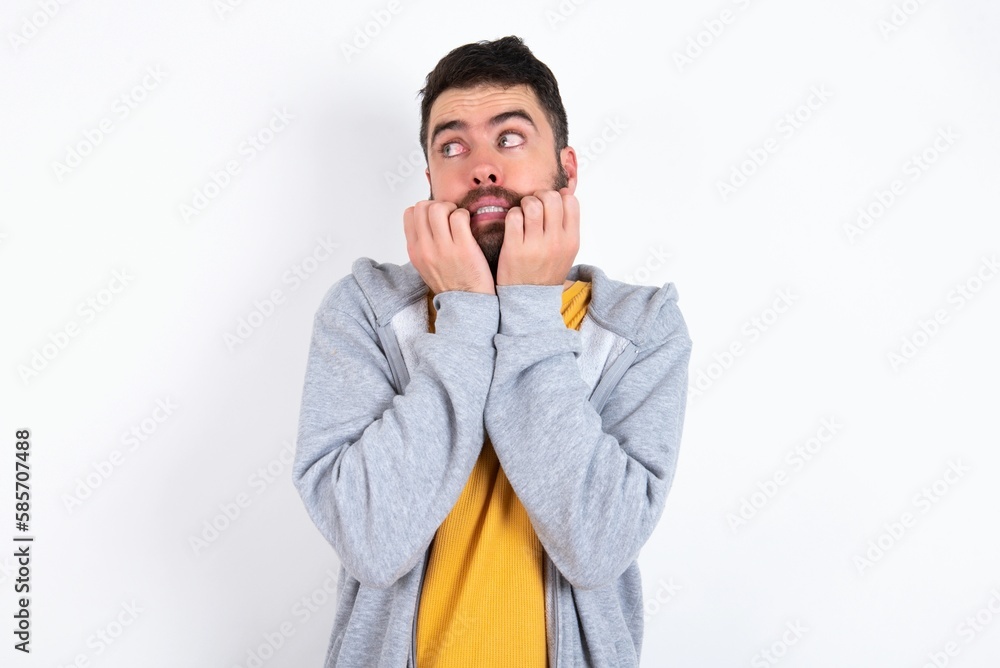 Terrified Young caucasian mán wearing trendy clothes over white background looks empty space home alone moonless night Terrified Young caucasian mán wearing trendy clothes over white background looks empty space home alone moonless night