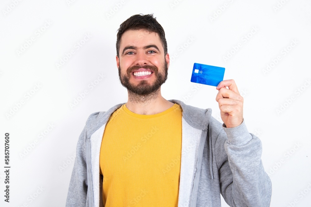 Photo of happy cheerful smiling positive Young caucasian mán wearing trendy clothes over white background recommend credit card