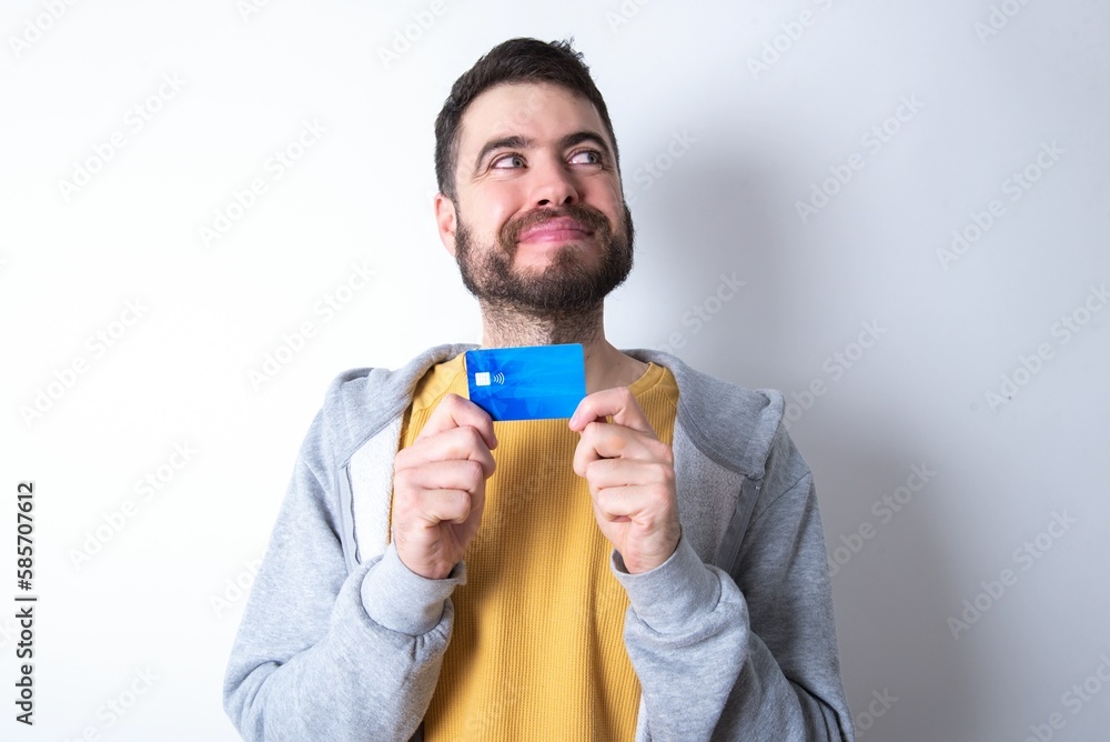 Photo of cheerful Young caucasian mán wearing trendy clothes over white background hold debit card look empty space Photo of cheerful Young caucasian mán wearing trendy clothes over white background hold debit card look empty space