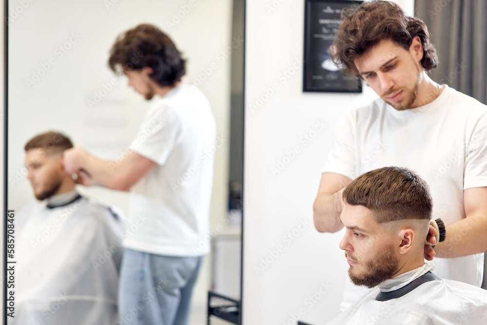 Obraz premium Barber trim hair with clipper on handsome bearded man