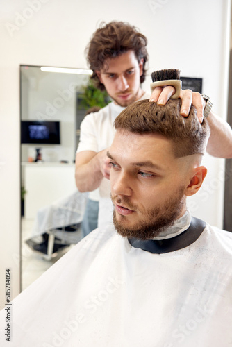 Barber trim hair with clipper on handsome bearded man