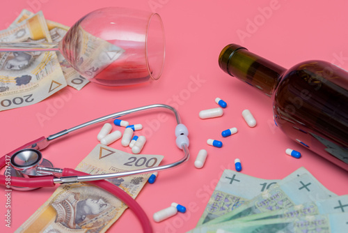 Butelka wina obok przewróconego kieliszka, tabletek i stetoskopu na różowym tle