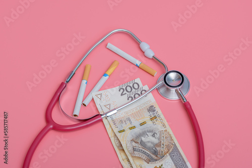 Papierosy leżące obok pieniędzy i stetoskopu 