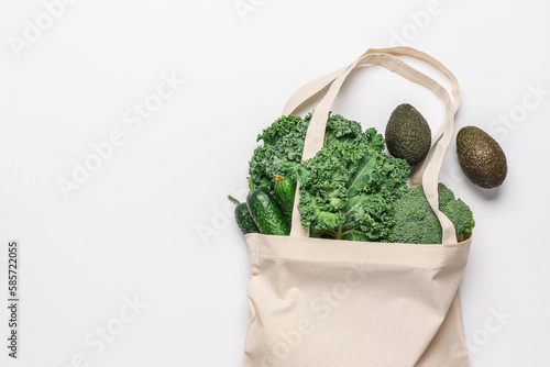 Cotton bag with green vegetables and fruits on white background. Zero waste grocery shopping. Sustainable lifestyle concept. Plastic free items