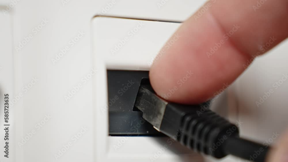 Hand connects ethernet RJ45 cable into socket. Connecting a cable to access the Internet, close up shot Hand connects ethernet RJ45 cable into socket. Connecting a cable to access the Internet, close up shot