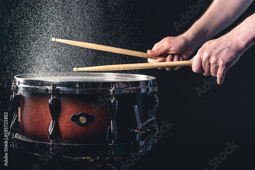 Obraz na plátně Drummer using drum sticks hitting snare drum with splashing water