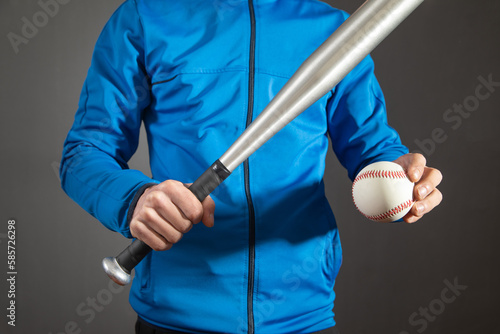 Caucasian man holding baseball bat and ball.