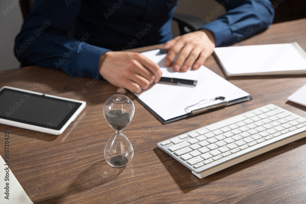 Businessman working at office with a hourglass on the table. Businessman working at office with a hourglass on the table.