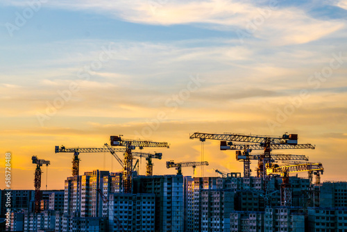 Photography Silhouette of cranes over new building construction site in eastern side of Sing