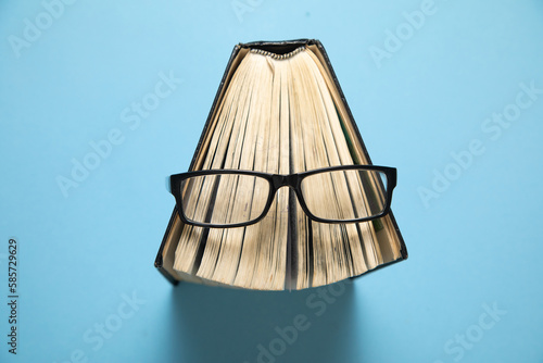 Eyeglasses and book on the blue background.