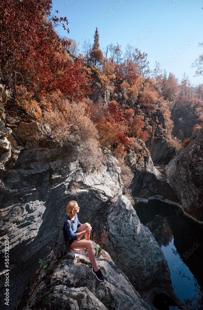 Obraz premium Active lifestyle. Trekking and hiking. Young woman with rucksack in the forest rock canyon.