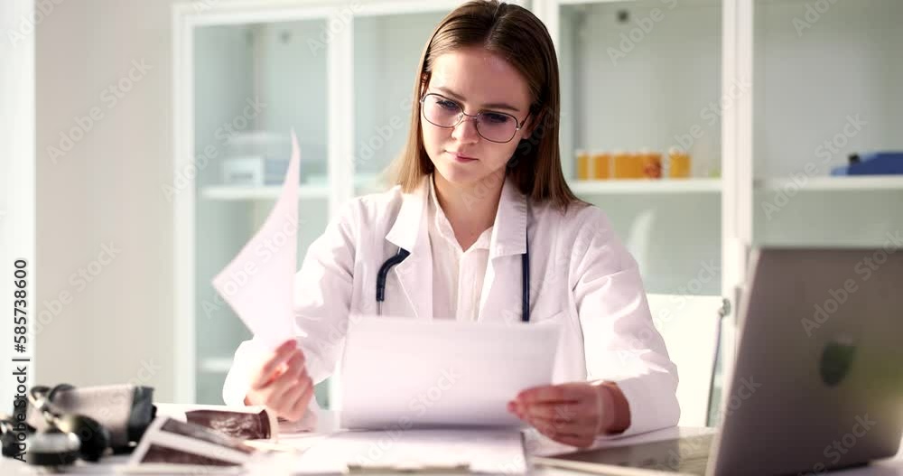 Focused female doctor looks at test results of patient Focused female doctor looks at test results of patient