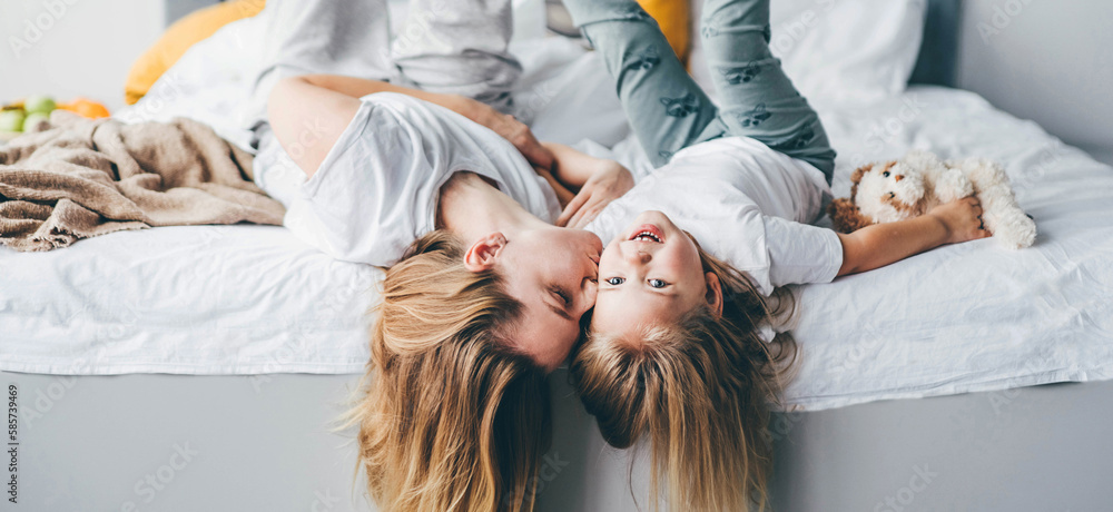 Happy mother and daughter having fun and playing together on the bed at home. Happy mother and daughter having fun and playing together on the bed at home.