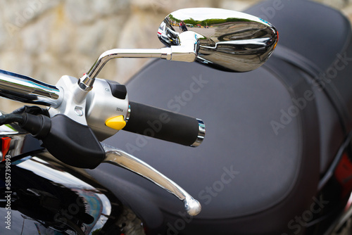 Close-up view of motorcycle handle with switches and mirror
