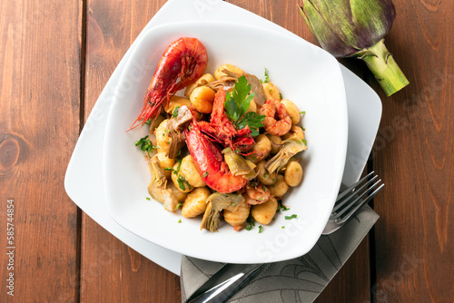 Gnocchi di patate conditi con carciofi e gamberi, cibo italiano  photo