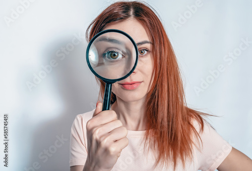 A woman's face through a magnifying glass. Long hair, big eyes. Research, choice concept.