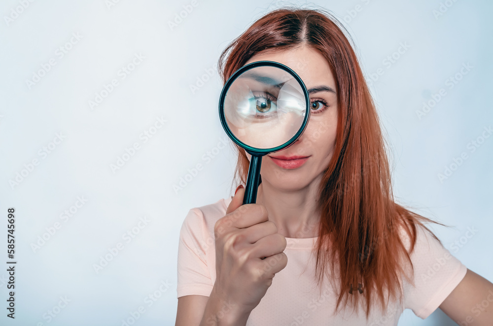 Magnifying glass. A woman's face through a magnifying glass. Long hair, big eyes. Research, choice concept. Magnifying glass. A woman's face through a magnifying glass. Long hair, big eyes. Research, choice concept.