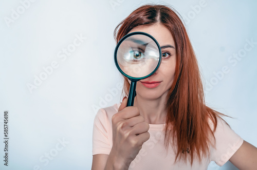 Magnifying glass. A woman's face through a magnifying glass. Long hair, big eyes. Research, choice concept.