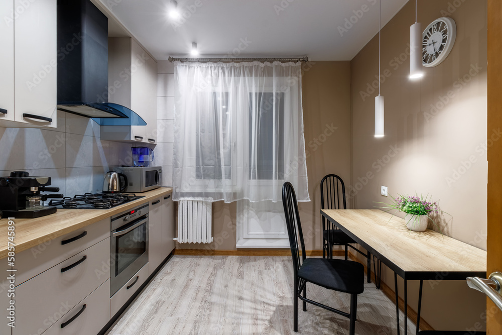 View of a modern kitchen with blue hood, kitchen appliances and dining table