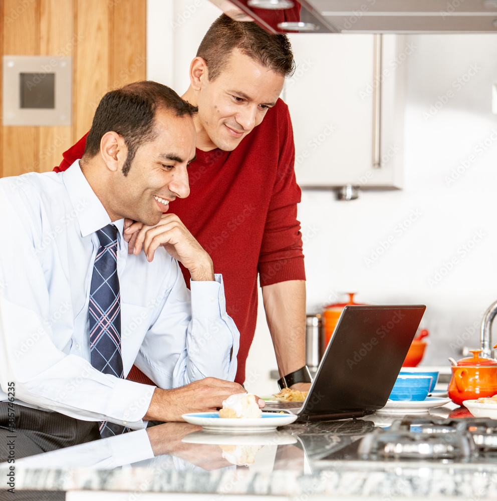 Gay Lifestyle: Modern Communication. A same sex, mixed race couple using a laptop computer together over breakfast. From a series of related images. Gay Lifestyle: Modern Communication. A same sex, mixed race couple using a laptop computer together over breakfast. From a series of related images.