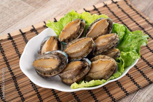 Delicious raw abalone in a plate on wooden table background. photo
