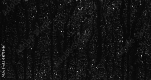 Drops of water flowing down the glass on a black background