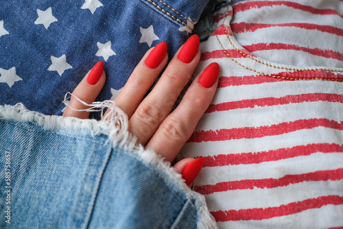 Beautiful female hands with a bright red matte manicure on the background of jeans. Stylish oval nail design, American style. Summer manicure. Copy space. photo