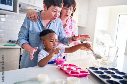 Lesbian couple and cute son baking heart-shape cupcakes in kitchen