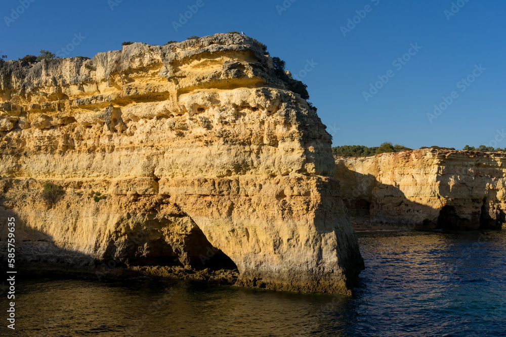 Landscape of Albandeira beach, cliffs, and natural arch in the Algave region at sunset. Portugal.