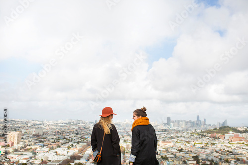 Rear view of two women standing in front of cityscape