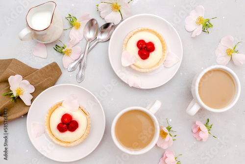 Delicious red raspberry strawberry whipped creamy tartlets,cakes.gourmet confection dessert on plate with latte coffee,milk.sweet tasty pastry baked pie cheesecake with ripe berries on gray table