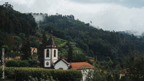 idyllic village in a mountain scenery with a church hidden among the trees. charming villages. a quiet place to live