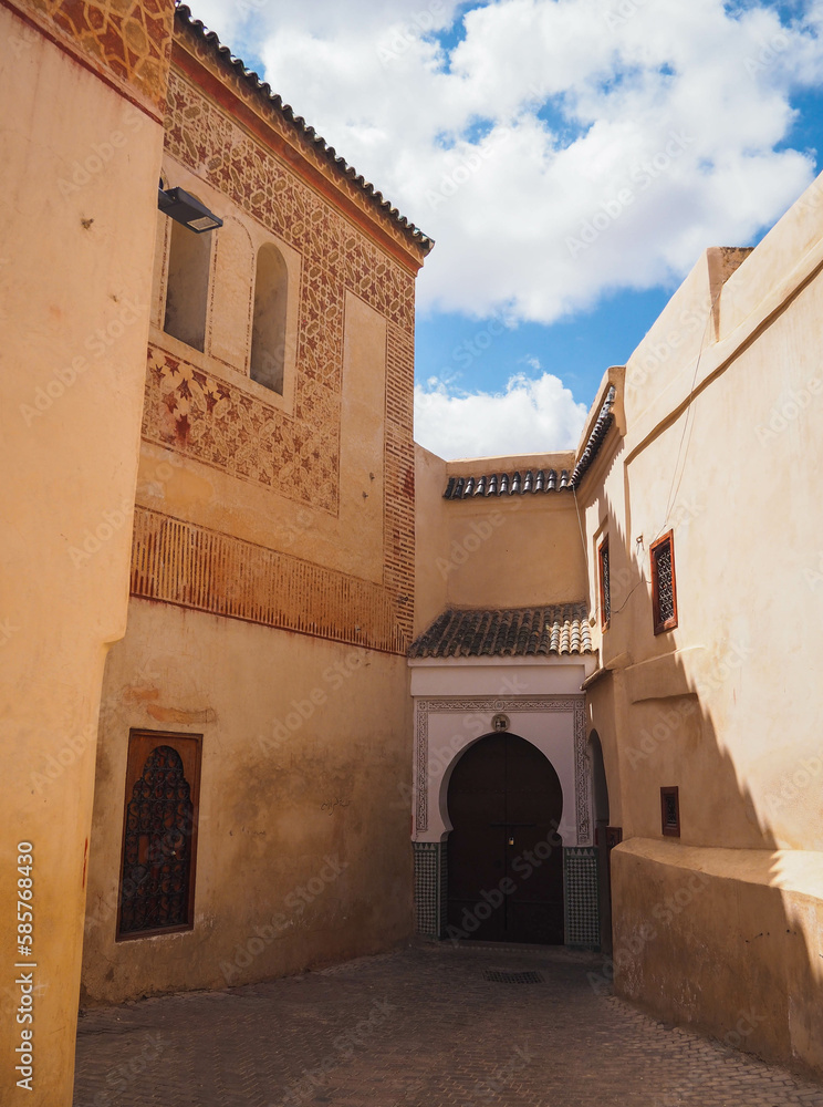 Rays of light in the dusty streets and alleys of the Medina of Marrakech, Morocco, dark city with sunlight, shadow and orange doors and gates