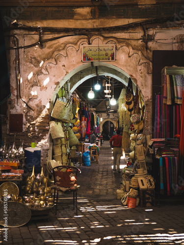 Busy Souk market street in the heart of the Medina of Marrakech, Morocco, dark street with sunlight