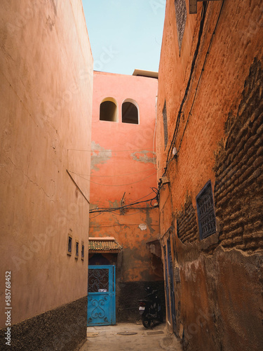 Alley leading to a blue door of a residential building in the streets of the Medina of Marrakech, Morocco, dark street with blue sky