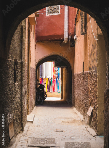 Arch in a residential area in the streets and alleys of the Medina of Marrakech, Morocco, with a bike and colorful clothes of the Souk next to it