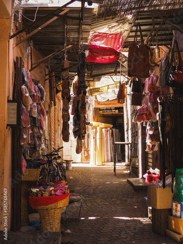 Rays of light in the dusty streets and alleys of the Medina of Marrakech, Morocco, dark city with sunlight and parked bikes and wares