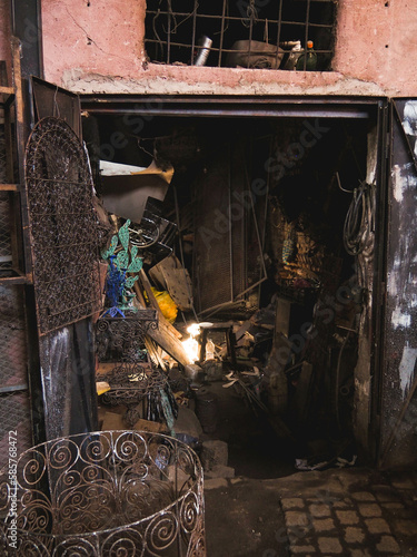 Rays of light in a dark, crowded garage in the busy Souk market alley selling and welding metal wares in the heart of the Medina of Marrakech, Morocco, dark street with sunlight