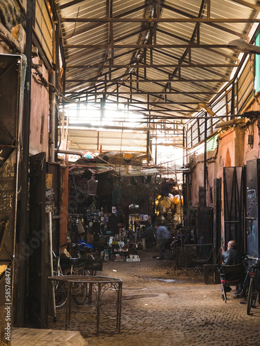 Busy Souk market alley selling and welding metal wares in the heart of the Medina of Marrakech, Morocco, dark street with sunlight