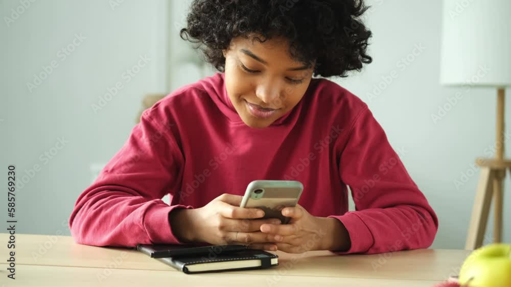 African girl holding smartphone touch screen typing scroll page at home. Woman with cell phone surfing internet using social media apps playing game. Shopping online Internet news cellphone addiction African girl holding smartphone touch screen typing scroll page at home. Woman with cell phone surfing internet using social media apps playing game. Shopping online Internet news cellphone addiction