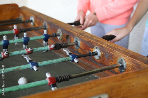 Children playing metegol. Foosball. Soccer hall game. Traditional game. Soccer game. Table with soccer players. Old wooden foosball. Football players. Dolls with blue and red painted T-shirts.