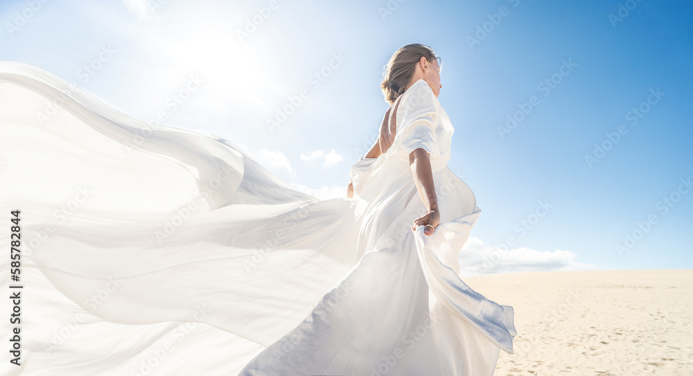Photo of a woman in amazing white wedding dress posing on the desert, sunny light, blue sky,