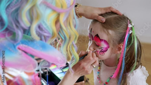 Children face painting. Artist painting little preschooler girl like unicorn on a birthday party. Creative activities for kids
