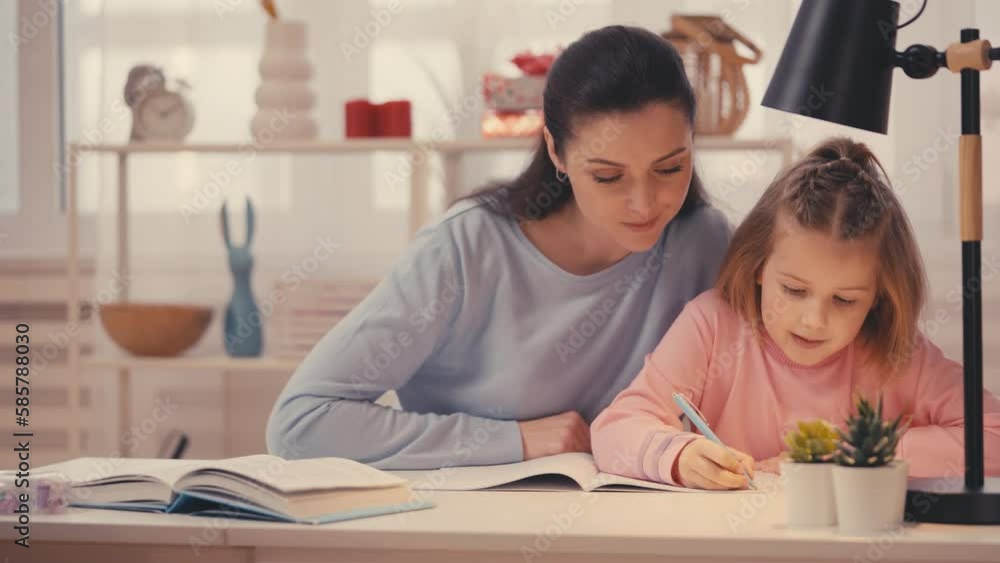 Caring mother helping little daughter with homework, encouraging her education Caring mother helping little daughter with homework, encouraging her education