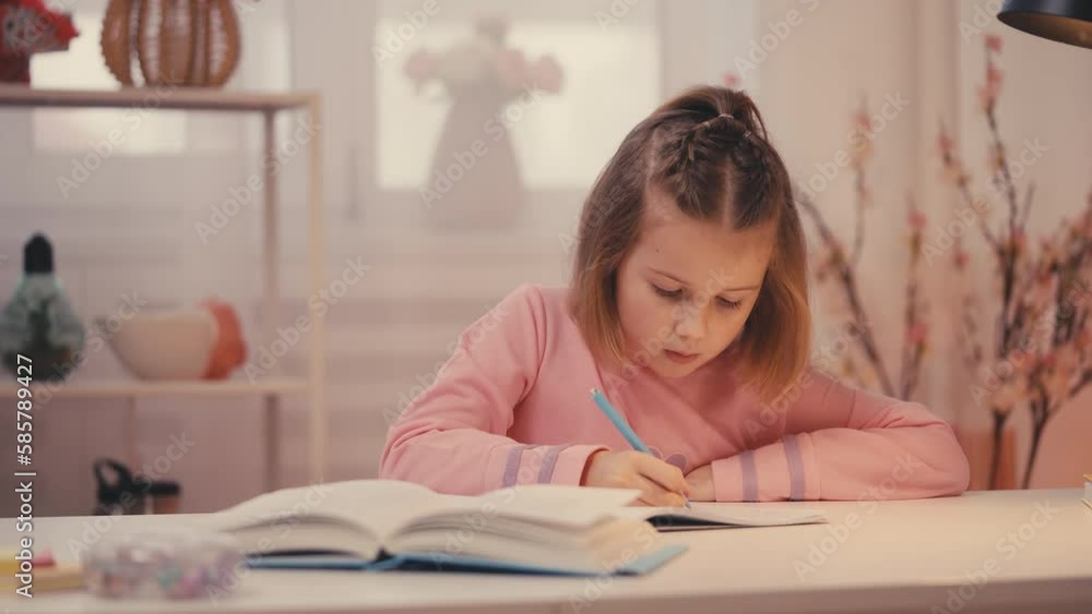 Concentrated girl doing homework and writing in notebook, home education Concentrated girl doing homework and writing in notebook, home education